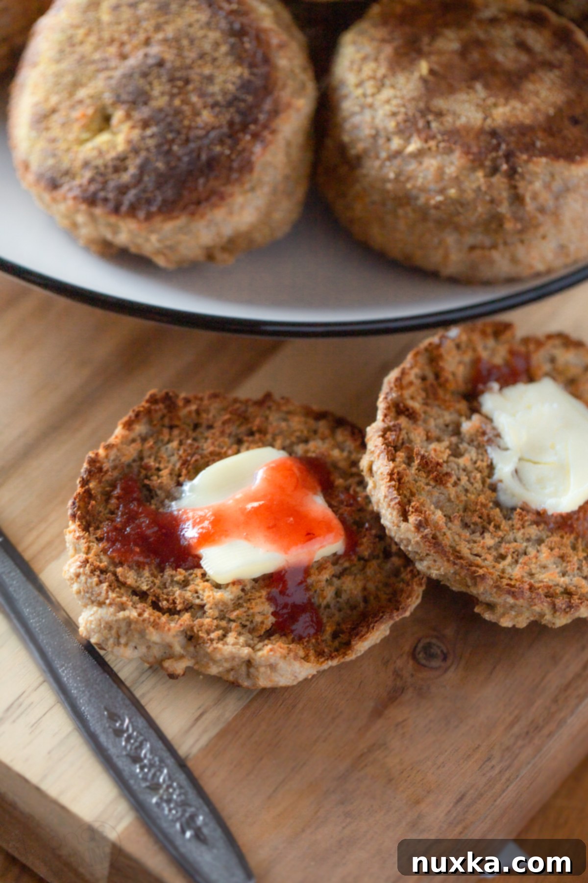 Toasted sourdough English muffins generously topped with butter and homemade jam for a delightful breakfast.