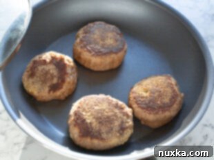 Close-up of sourdough English muffins cooking in a pan with a lid, no oil.