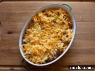 taco casserole recipe made in a 2-quart baking dish and layered with tortilla chips, beans, beef, and cheese. Top with taco topping like lettuce, tomatoes, and onion.