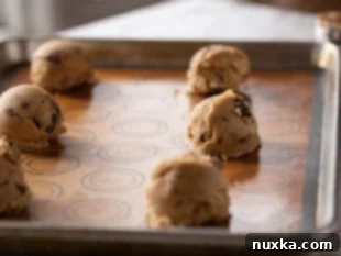 Arrangement of chocolate chip cookie dough balls on a baking sheet, ready to be baked into giant cookies