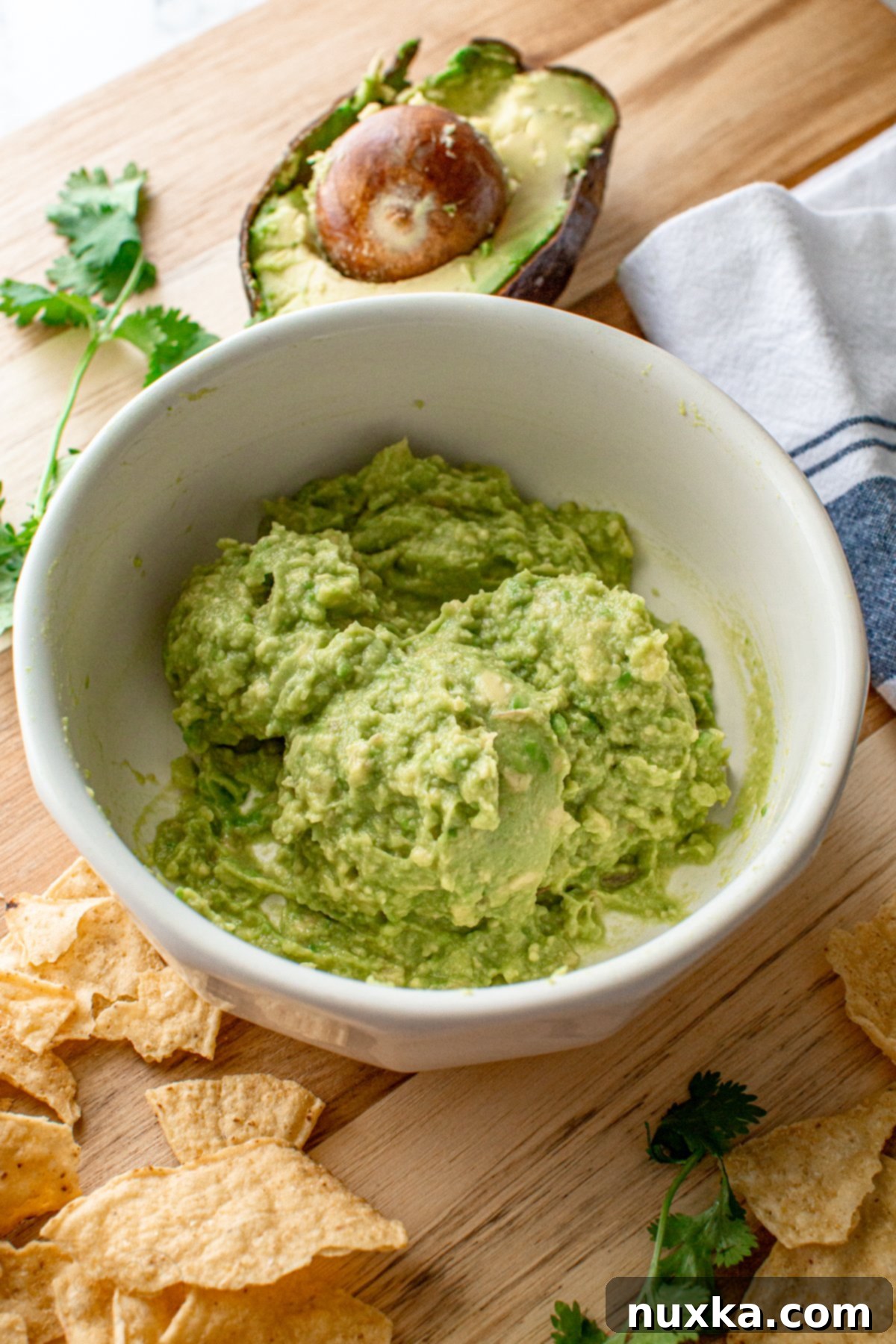 Close-up image of fresh, homemade simple guacamole in a bowl, garnished with a lime wedge