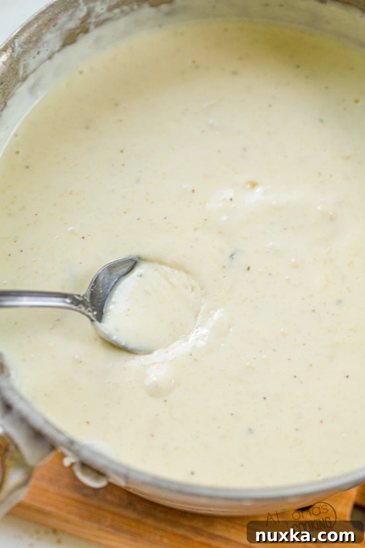 Homemade creamy garlic Alfredo sauce in a saucepan, made from dry ingredients and heavy cream, ready to serve.