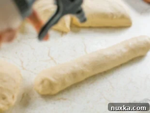 Spraying the tops of sub roll dough with water before adding seasoning.