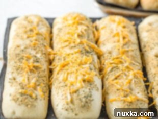 Sprinkling shredded cheese on risen Subway bread dough before baking.