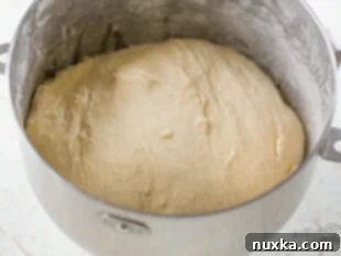 Bread flour being added to the wet ingredients in a stand mixer for Subway bread dough.