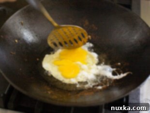 Scrambling eggs and adding rice for fried rice base