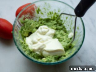 Mixing mayonnaise and garlic into mashed avocado.