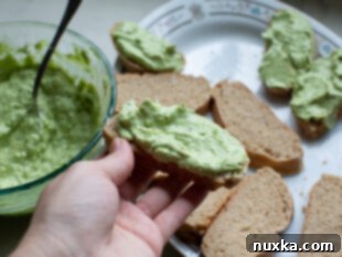Assembling avocado toast sandwiches with tomato and black pepper.