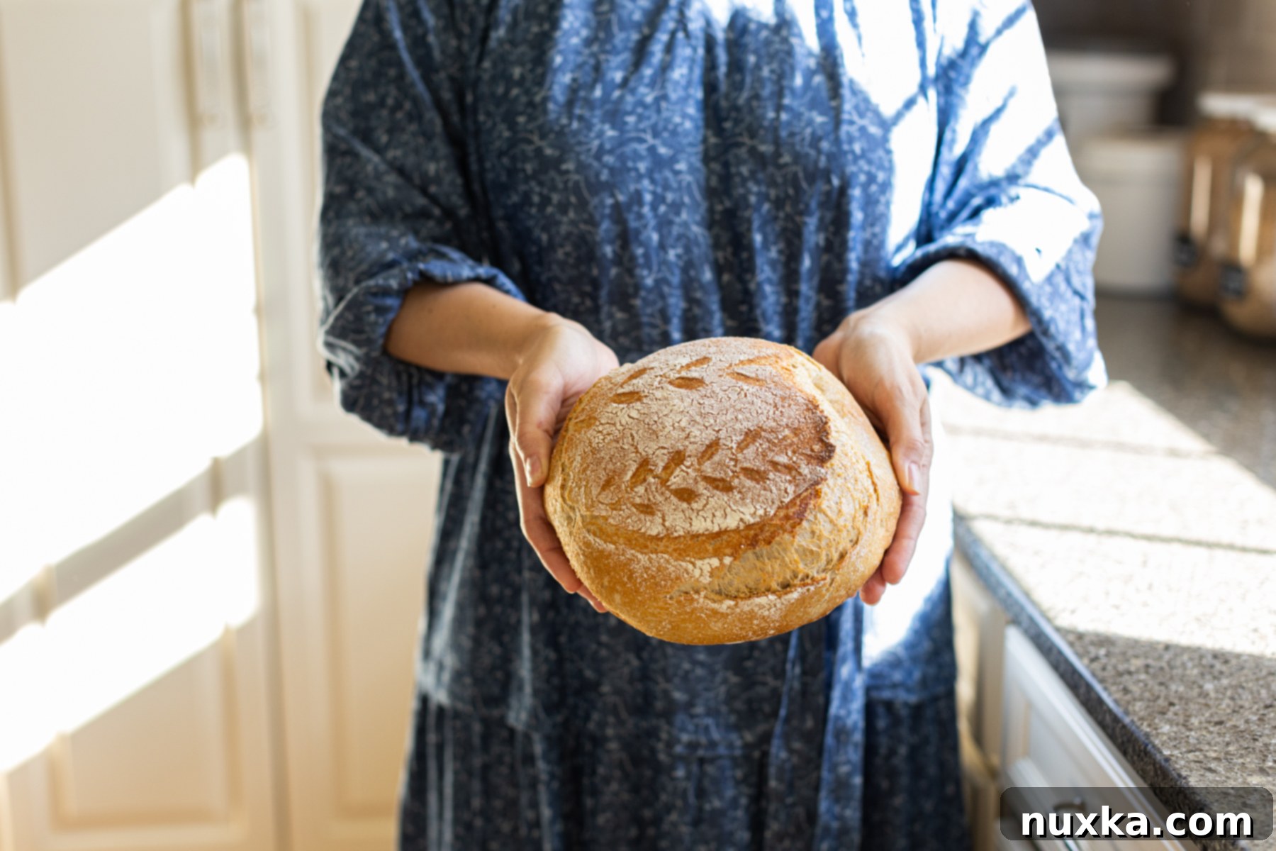 holding a homemade whole wheat sourdough boule