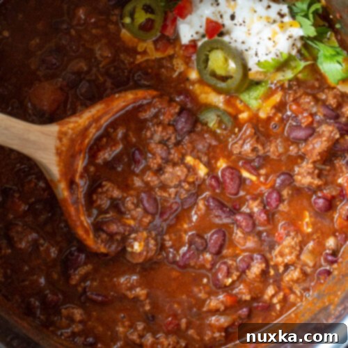 Easy Instant Pot Chili 2 Instant Pot chili recipe in a bowl with a spoon, garnished with sour cream and green onions