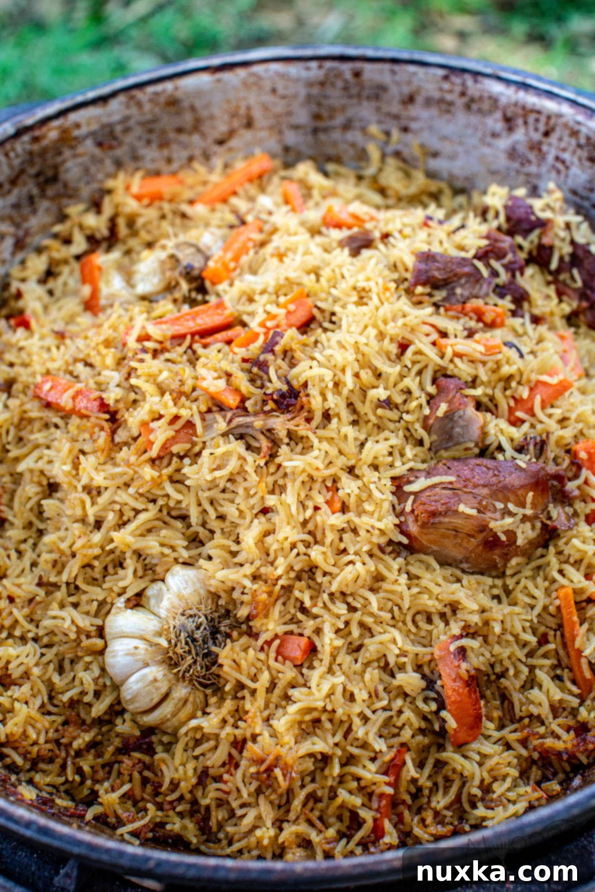 Traditional Uzbek Plov made in a large Kazan with tender meat, vibrant carrots, and aromatic spices