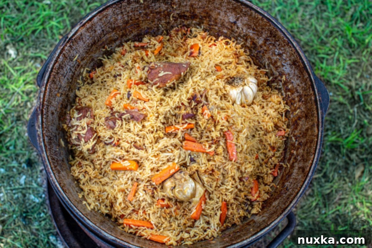 Uzbek Plov with Zervak simmering in a Kazan, showing the rich base of meat, carrots, and onions