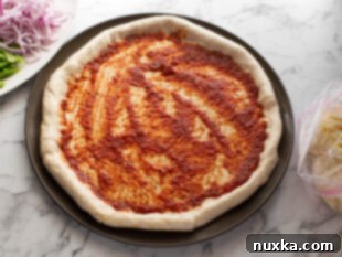 spreading marinara sauce on stuffed crust pizza
