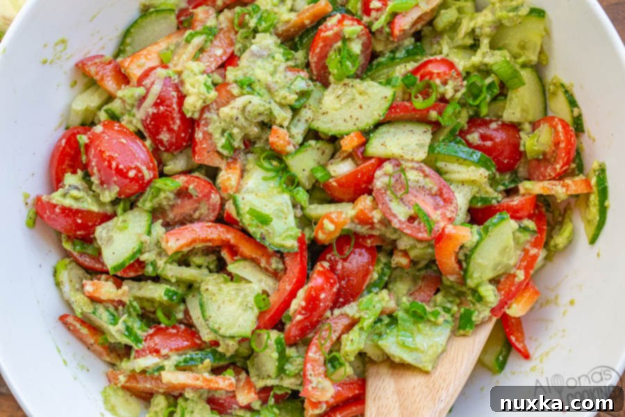 A large salad bowl filled with creamy cucumber tomato avocado salad, ready to serve.