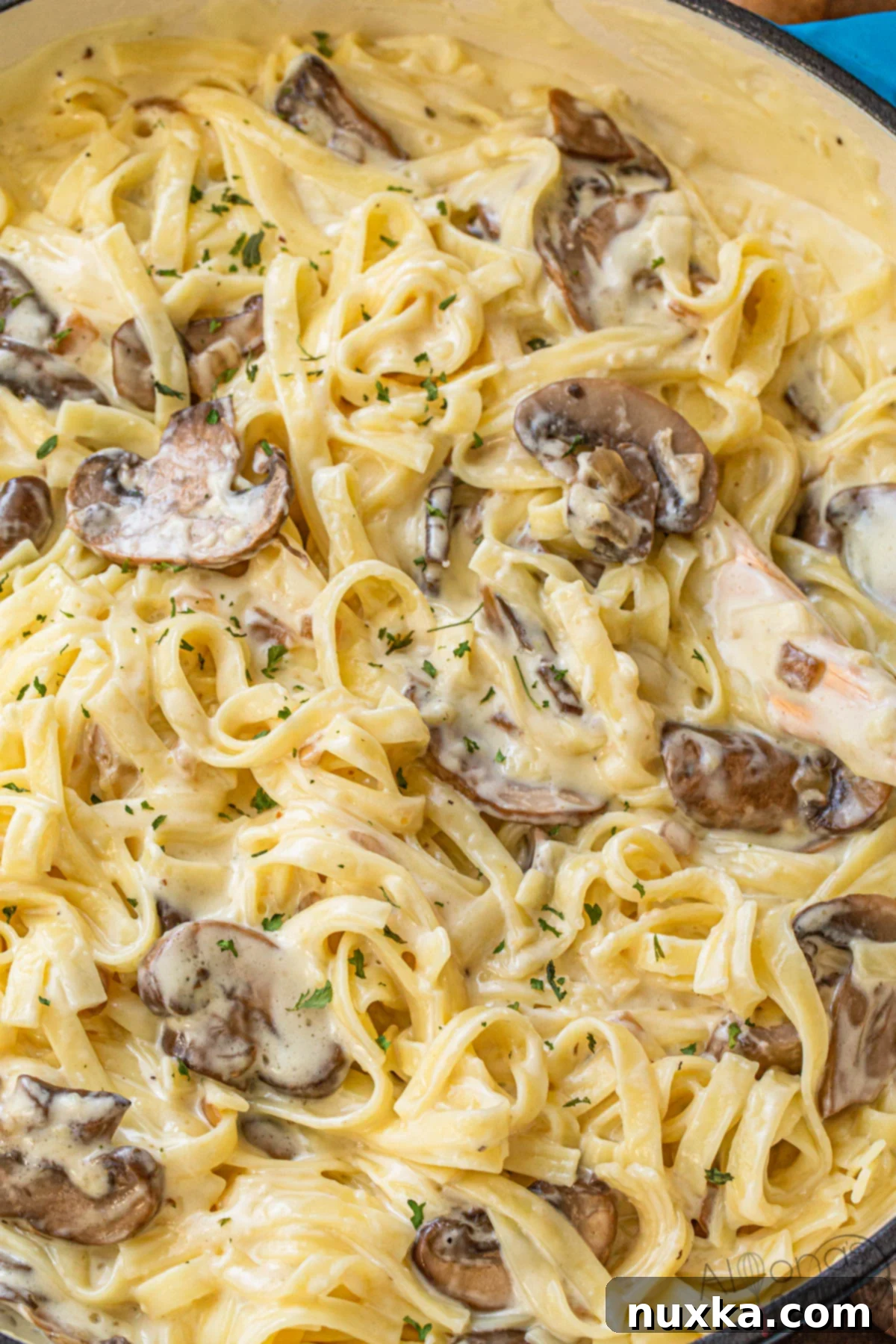 fettuccine Alfredo with mushrooms, showcasing a forkful of pasta with mushrooms and creamy sauce