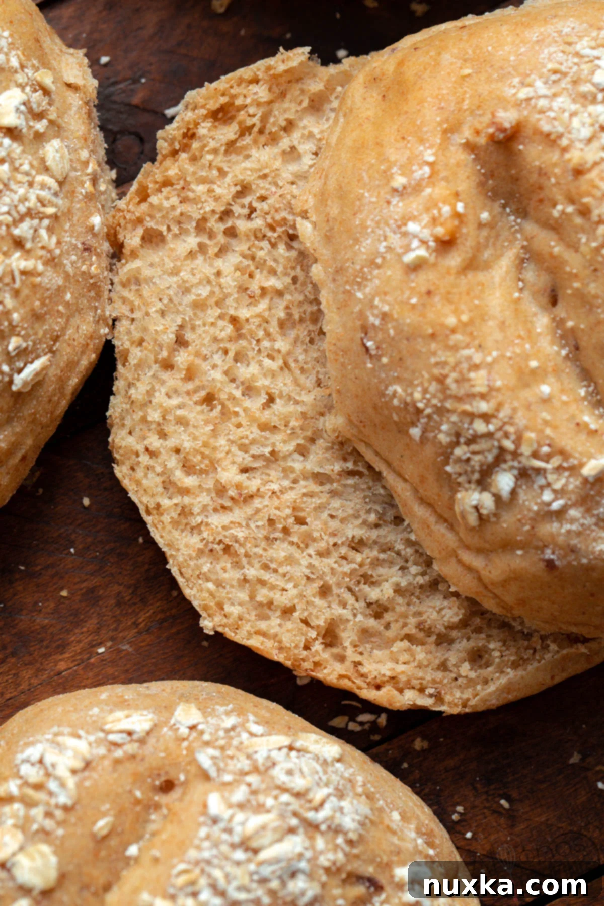 A stack of golden-brown, feather-light homemade whole wheat hamburger buns, showcasing their soft texture and perfect shape, ready for serving.