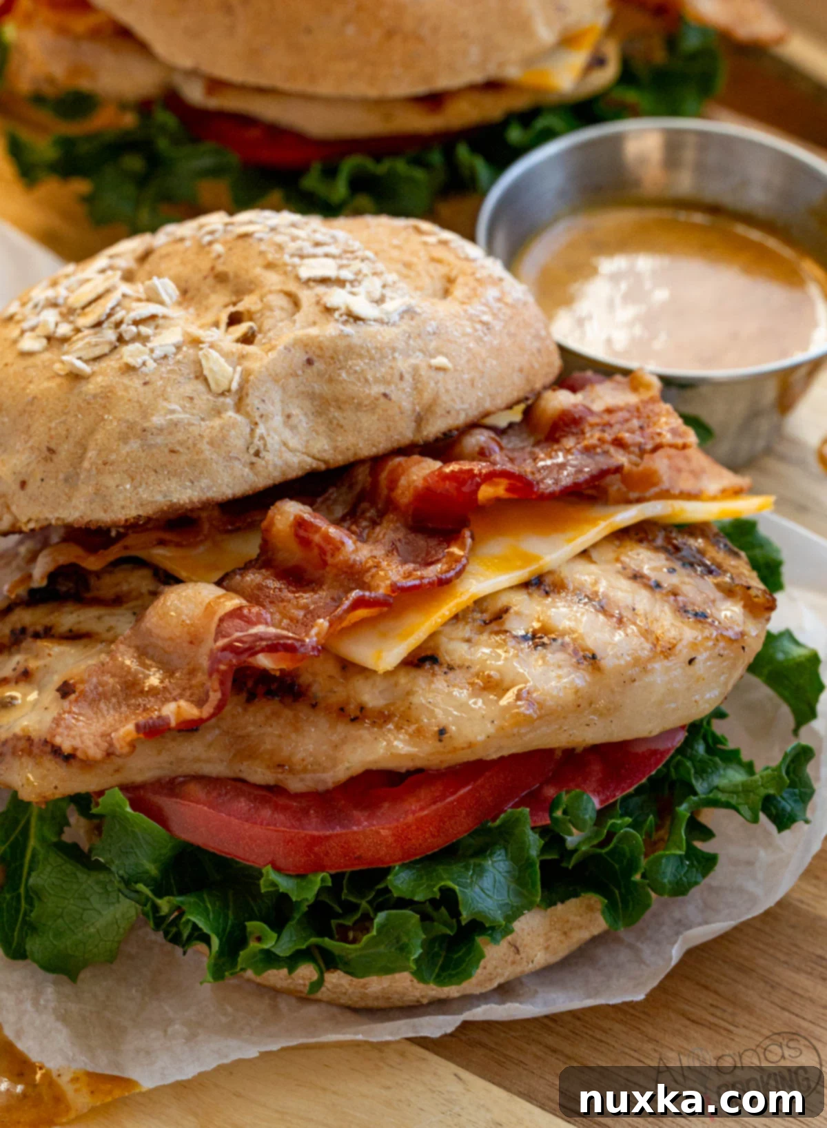 homemade chick fil a grilled chicken sandwich on a multigrain brioche bun, green leafy lettuce, tomatoes, Colby jack cheese, and Honey roasted bbq sauce (Chick fil a sauce)