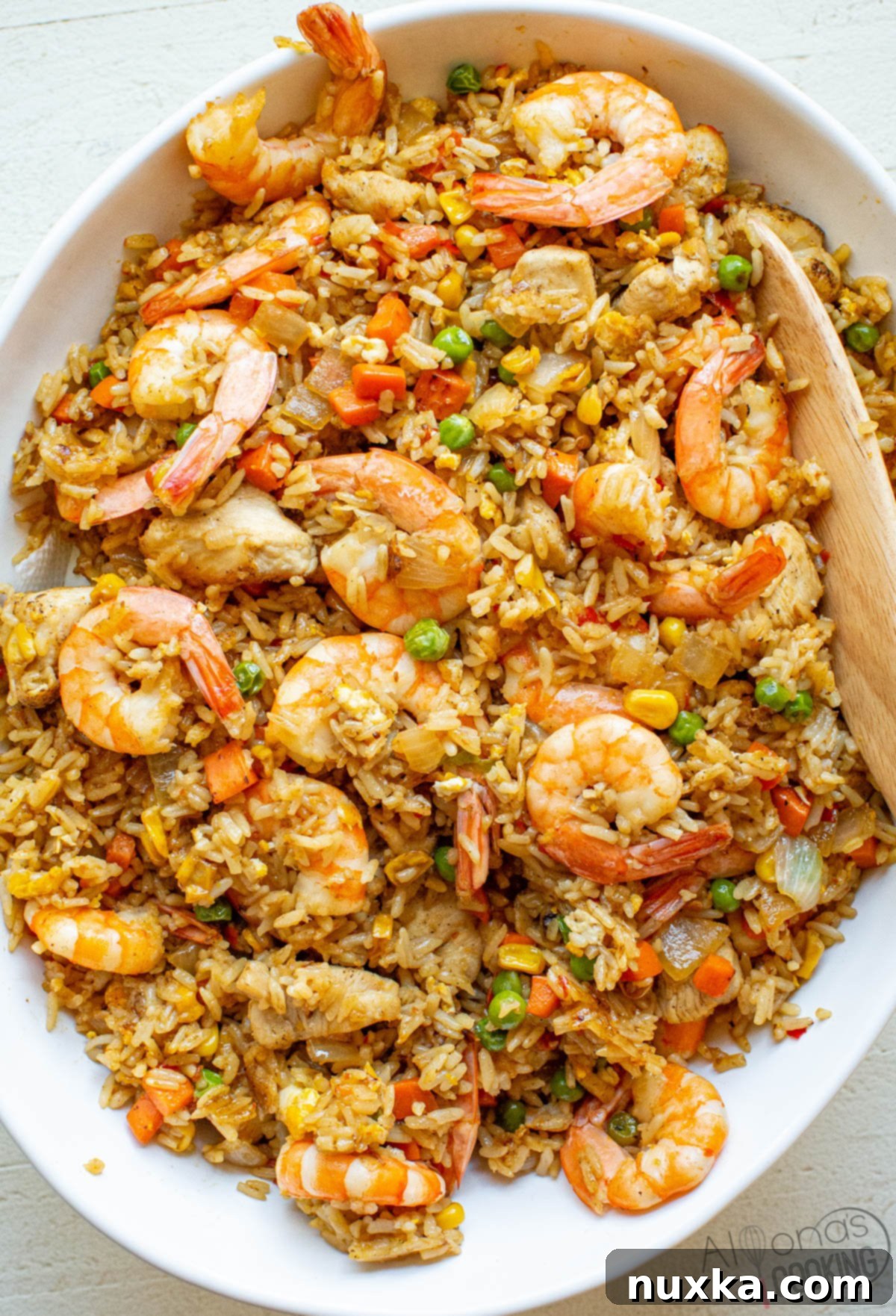 image of homemade shrimp fried rice with carrots, peas, onion, chicken, eggs, sauces, and jasmine rice, presented in a bowl ready to serve.