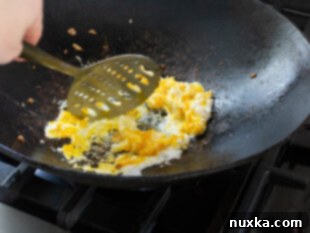 Scrambling eggs in a hot wok for homemade fried rice