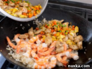 How to combine all ingredients including rice, chicken, shrimp, vegetables, eggs, soy sauce, and sweet chili sauce to make homemade fried rice in a wok
