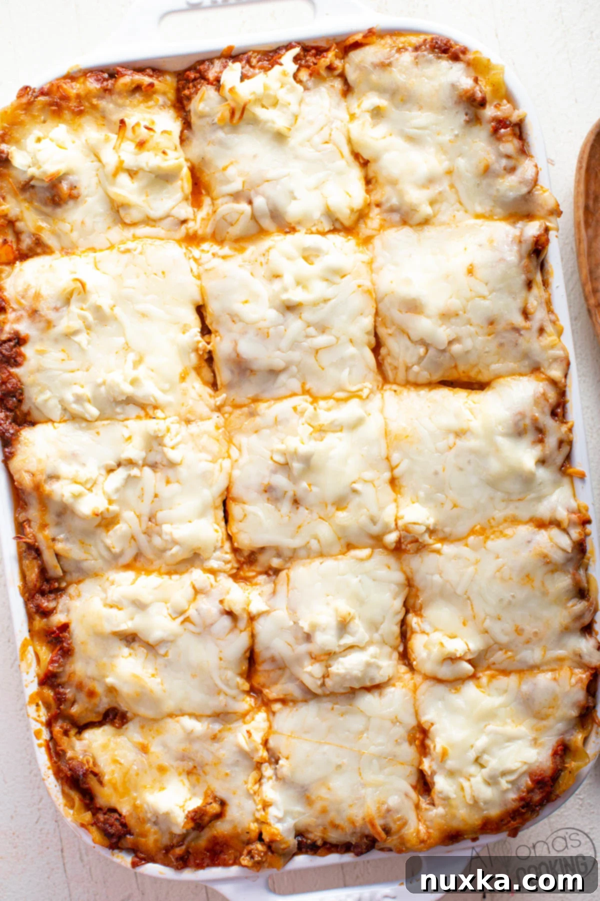 The BEST cream cheese lasagna recipe in a casserole pan, featuring wide pasta sheets, a rich meat sauce, grated cream cheese, and abundant mozzarella cheese, ready to be served.