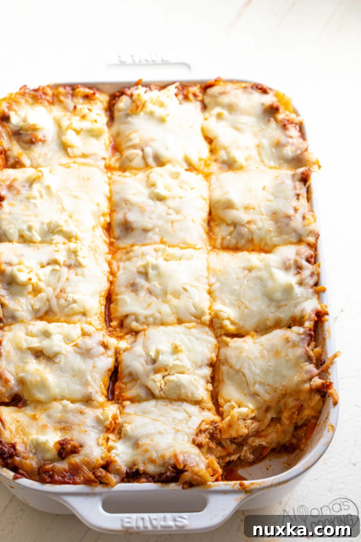 Delicious homemade lasagna made with traditional lasagna pasta noodles, a rich meat sauce, generous layers of cream cheese, and gooey mozzarella cheese, deliberately omitting ricotta or cottage cheese for a unique creamy texture.