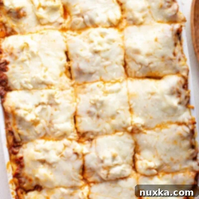 The ultimate cream cheese lasagna recipe, featuring wide pasta sheets, a rich meat sauce, grated cream cheese, and mozzarella cheese baked to perfection in a casserole dish.