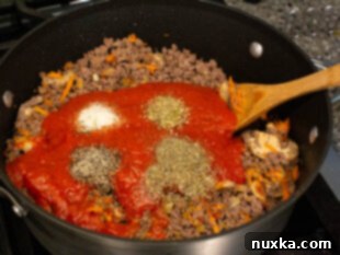 Preparing the rich meat sauce for cream cheese lasagna, combining traditional pasta sauce, canned mushrooms, shredded carrot, diced onion, and various spices and seasonings.