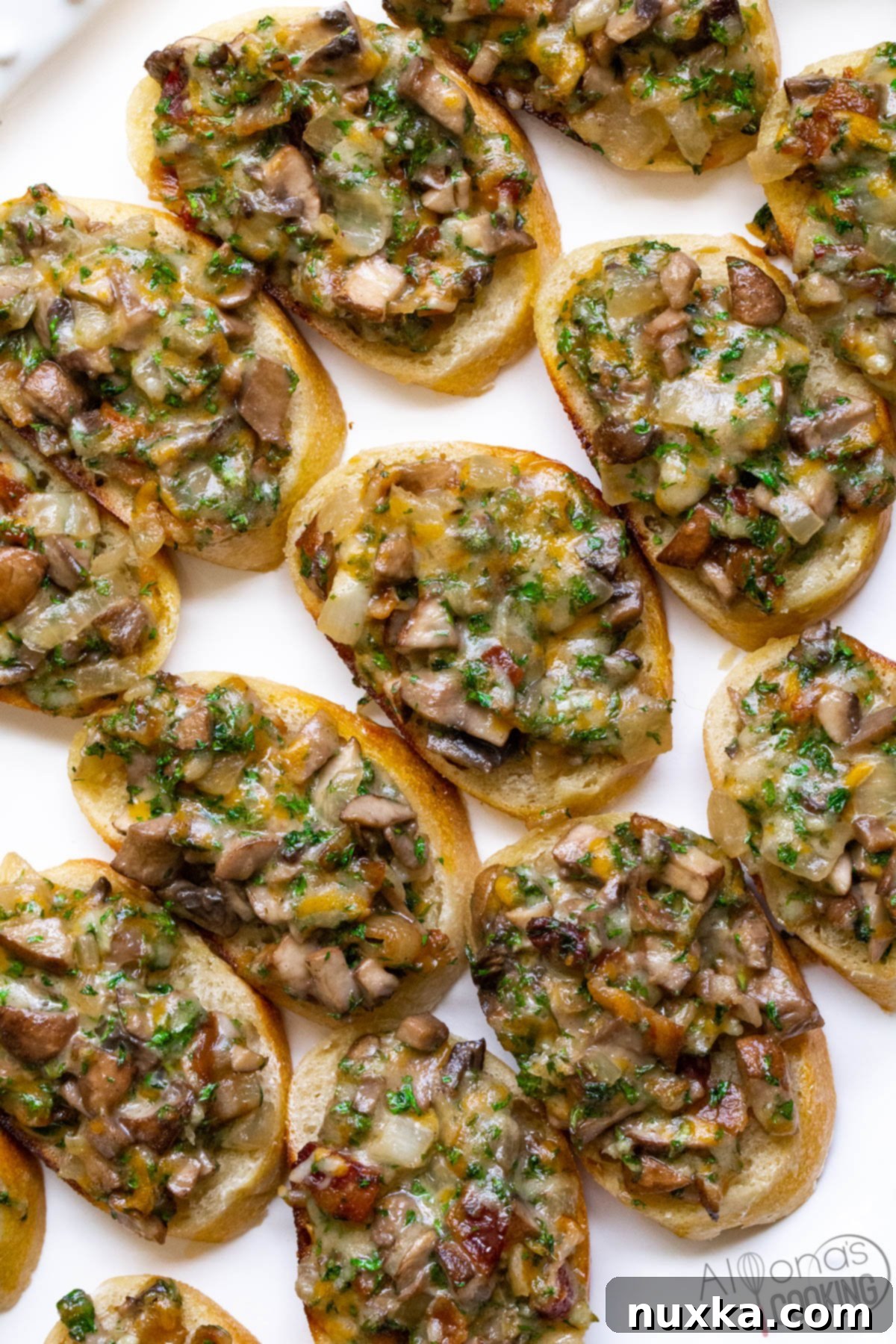 A large white platter filled with baked hot mushroom canapés, golden brown and garnished with fresh herbs, ready for serving.