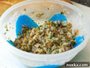 Mushroom canapé topping ingredients mixed in a bowl, showing cheese, mushrooms, and herbs