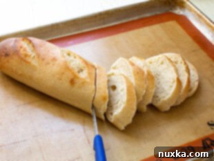 French bread slices arranged on a baking sheet, ready for topping with mushroom mixture.