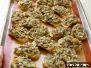 Hot mushroom canapés baking in the oven on a sheet pan, cheese melting and bubbling.