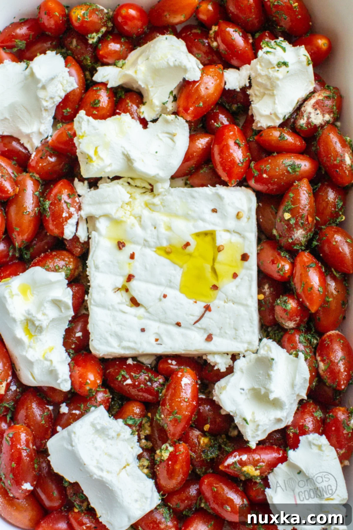 baked feta pasta recipe in a casserole baking dish with cherry tomatoes, feta cheese, and cream cheese, ready to be mixed