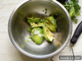 Mash ripe avocados with salt and citrus juices in a bowl for guacamole.