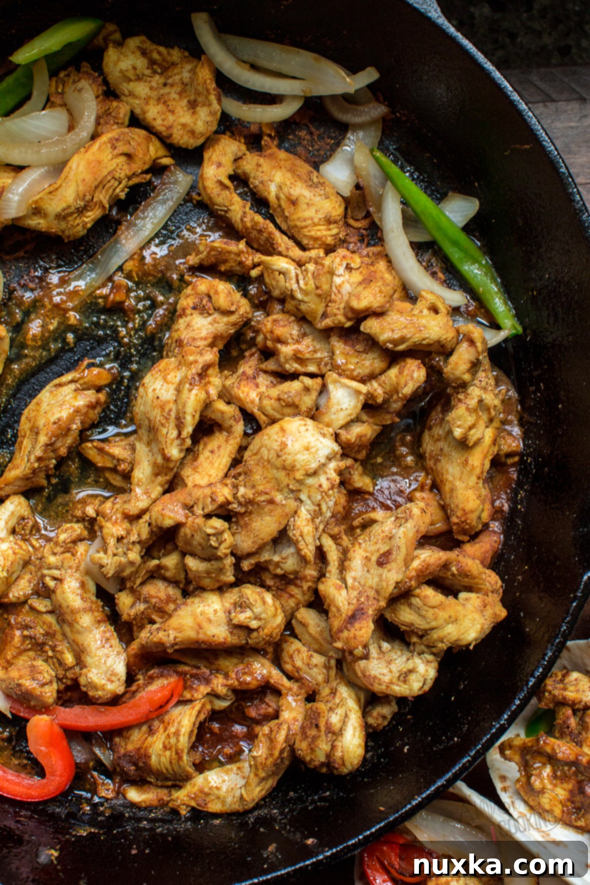 fajitas in a cast iron skillet, with chicken, onions, and bell peppers sizzling