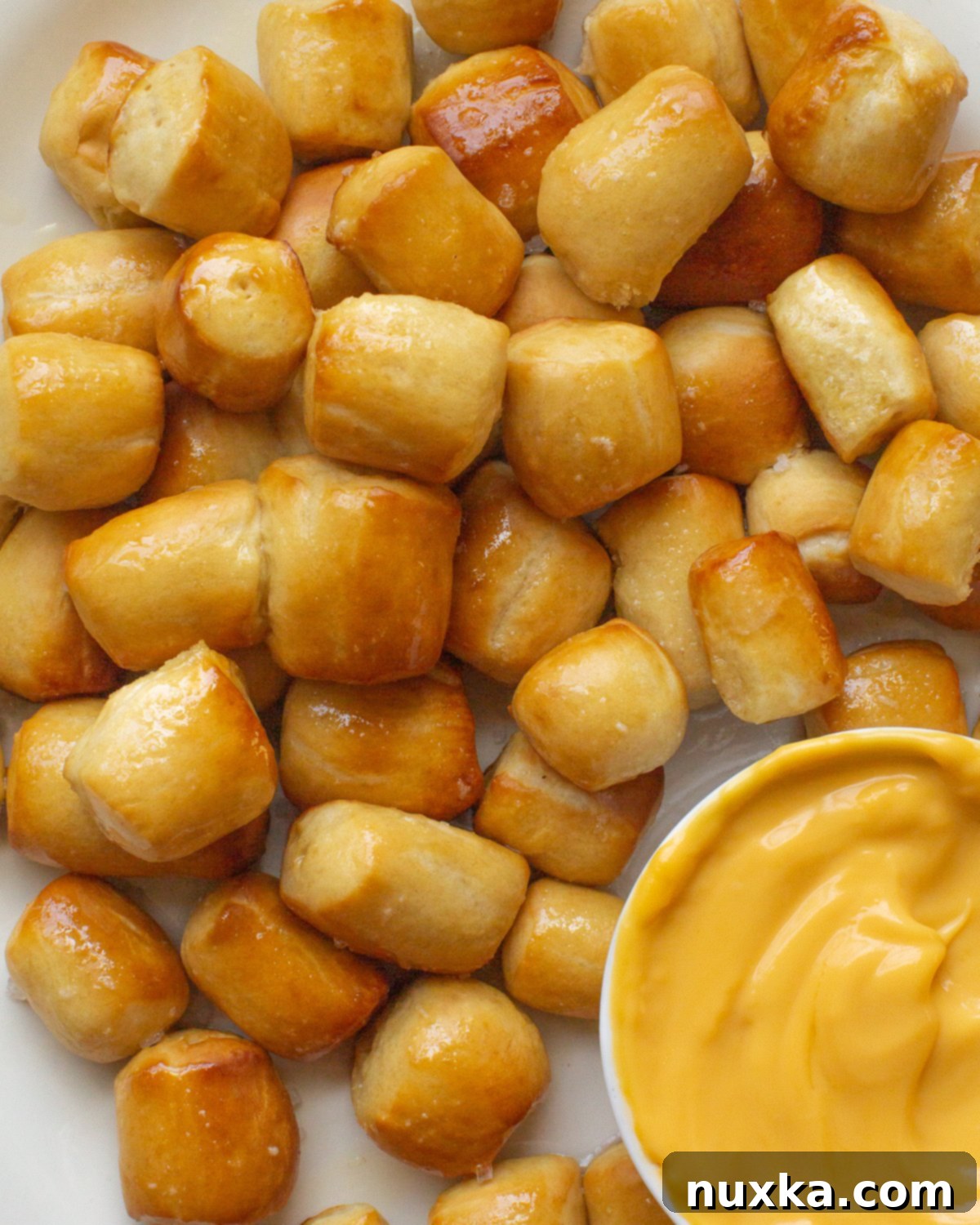 Delicious soft pretzel bites served with a rich cheddar cheese dip, perfect for a homemade snack experience.