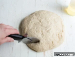 Cutting pretzel dough with a pizza cutter into strips