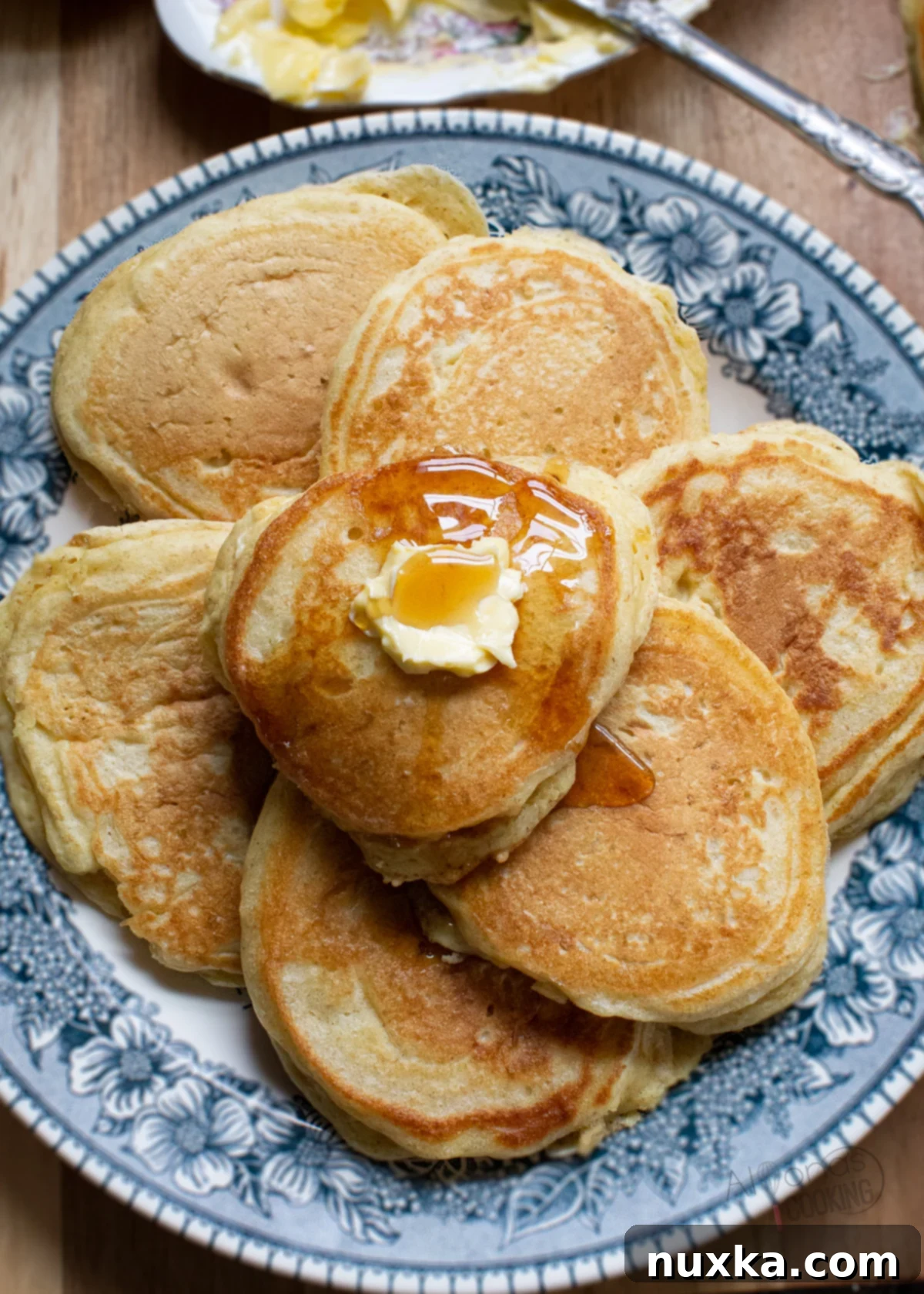 Fluffy homemade pancakes stacked high, drizzled with maple syrup