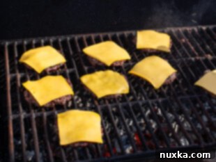 Venison burgers topped with melting cheese on the grill