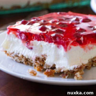 Jeweled Pretzel Delight 3 Pomegranate Pretzel Salad, a layered dessert with a pretzel crust, cream cheese, and jello with pomegranate seeds