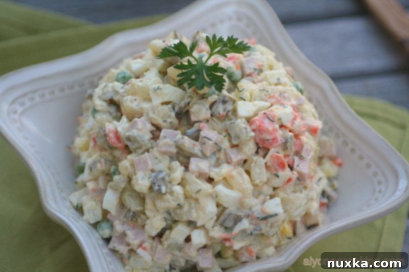 A large bowl of Olivye Salad, showcasing its inviting creamy texture and vibrant mixture of ingredients, perfect for sharing.