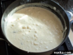 Creamy mushroom Alfredo sauce simmering in a skillet