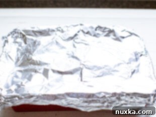 Assembled breakfast casserole covered with foil, ready for baking or overnight storage.