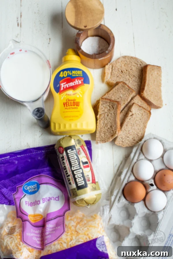 Collection of fresh ingredients for a sausage breakfast casserole: sausage, bread, cheese, eggs, milk, and seasonings, ready for preparation.