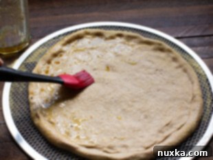 brushing whole wheat pizza dough with olive oil