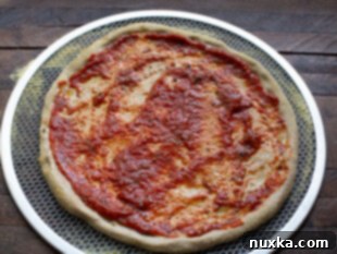 topping pizza dough with tomato sauce