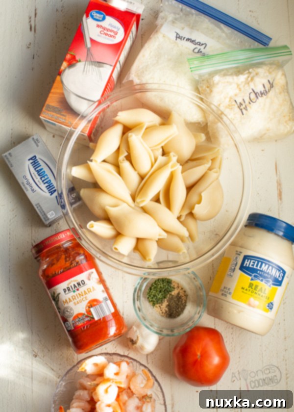 A collection of fresh ingredients laid out on a table, including pasta shells, cheeses, shrimp, cream, and tomatoes, ready for making stuffed shells.