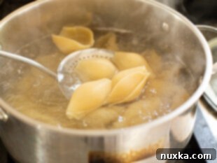 Boiling jumbo pasta shells in a large pot for shrimp stuffed shells recipe.