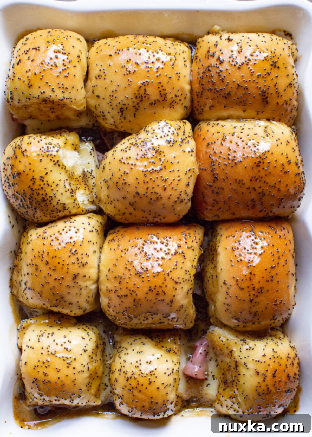 Delicious ham and cheese sliders topped with golden poppy seeds, baked to perfection for a party or quick meal.