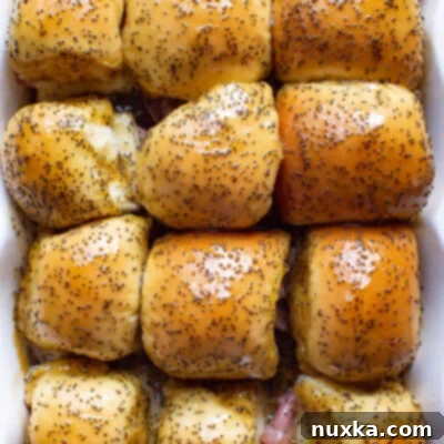 Baked Ham and Cheese Sliders 2 Baked ham and cheese sliders with melted cheese and a glossy poppy seed glaze, ready to serve.